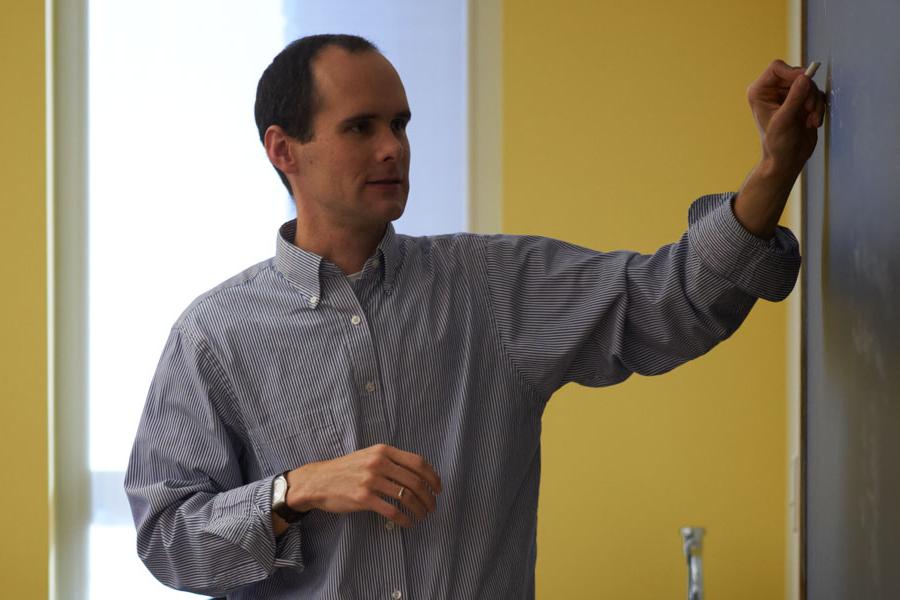 Professor writing on a board in a classroom