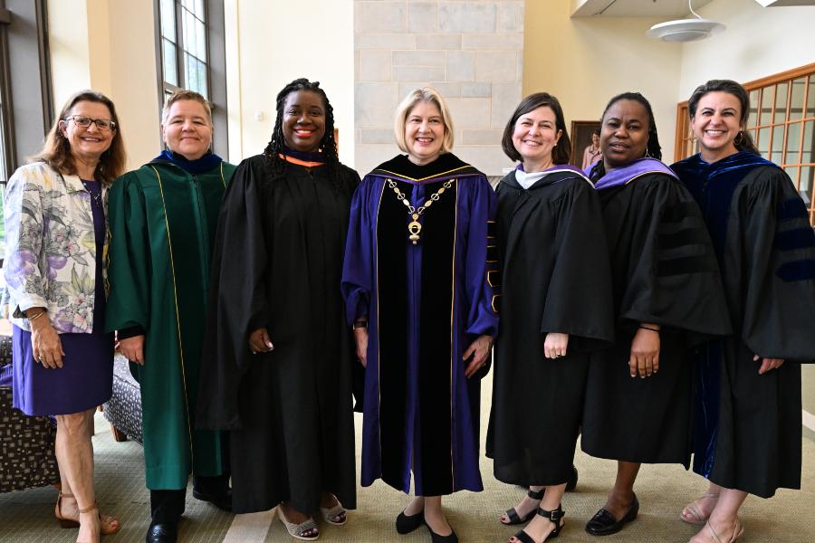 A group of college leaders pose for a photo, dressed in formal regalia